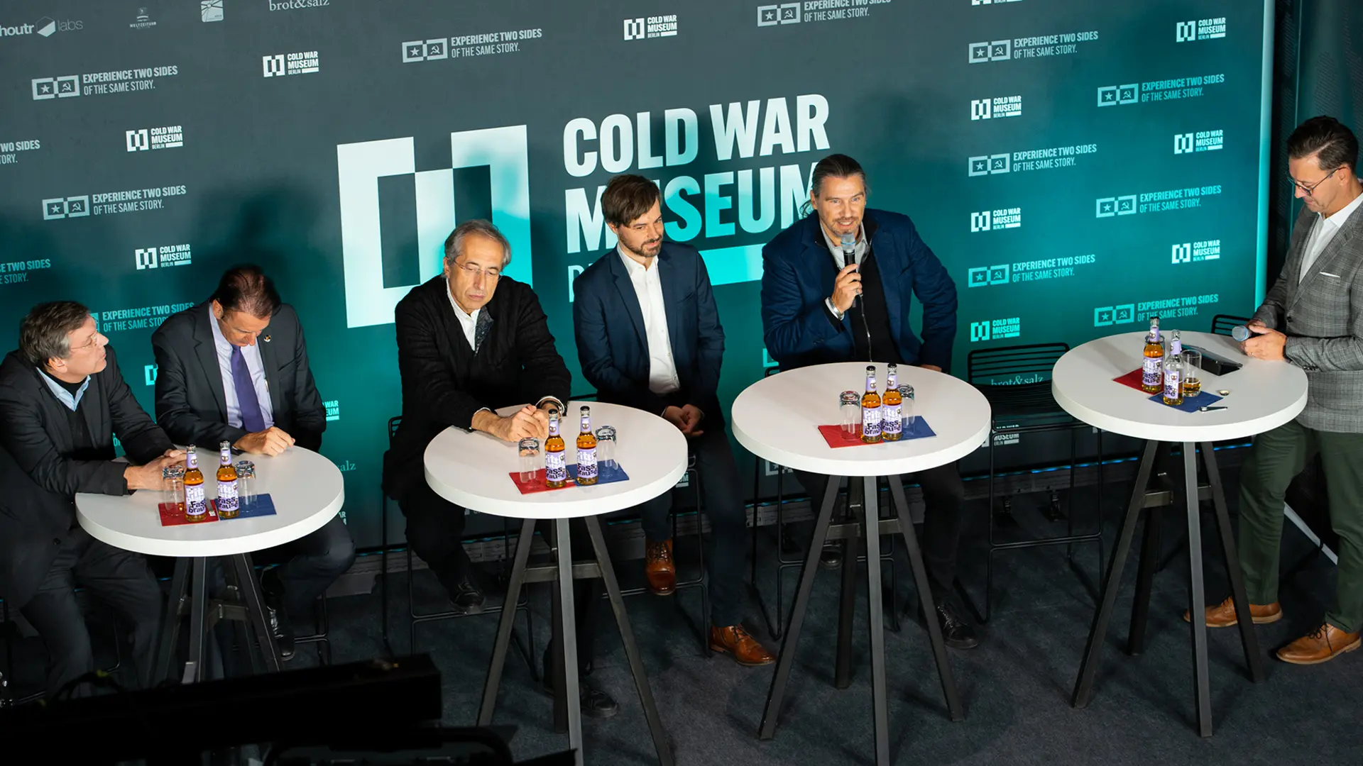 Ein Bild zeigt mehrere Personen vor einem Banner des Cold War Museum Berlin.